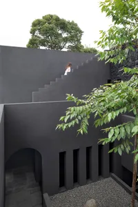A modern, minimalist interior with black concrete walls and stairs.