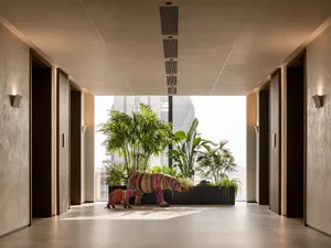 A modern entrance hall with concrete flooring, polished concrete walls, and lush indoor greenery featuring artwork.
