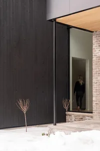 A modern building exterior featuring black wooden panels and concrete steps.