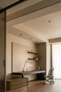 A modern home office featuring a light wood desk, shelves, and office chair.