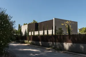 A modern house with a concrete exterior, surrounded by greenery.