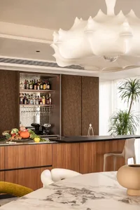 A modern kitchen bar area with wood cabinets and a marble countertop.