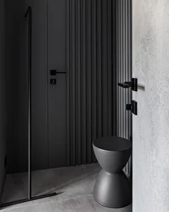 Modern minimalist bathroom featuring a sleek, black toilet and a textured concrete floor.