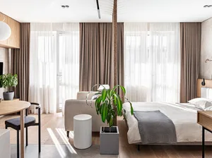A modern minimalist bedroom featuring neutral-toned furnishings and curtains.