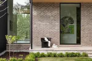 Modern minimalist residential interior featuring brick walls, concrete floors, and large glass windows.