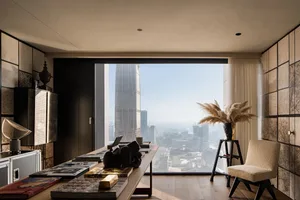 A modern office space featuring wooden floors, glass walls, and metallic accents.
