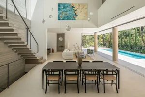 Contemporary residential interior featuring concrete walls and floors, a minimalist dining area, and a connection to an outdo