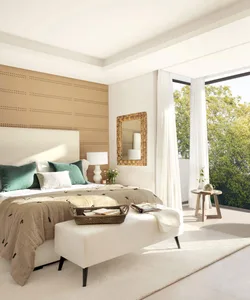 A minimalist bedroom featuring a bed with green and white pillows, a woven headboard, and a large window with sheer curtains,