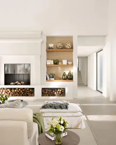 A modern minimalist living room with concrete walls, glass coffee table, and wooden shelves.