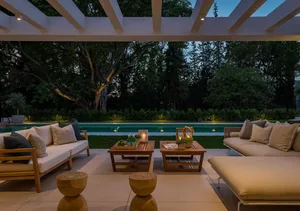 A minimalist patio with wooden furniture and a pergola.
