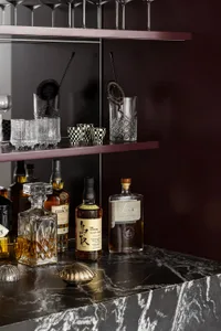 Modern bar counter made of marble with various bottles and glasses.