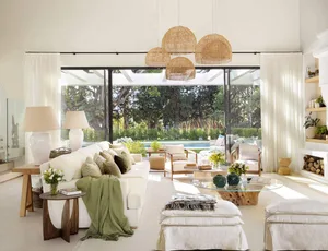 A modern living room with a white sofa, rattan pendant lights, and a glass coffee table.