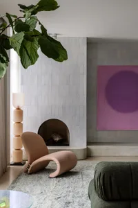 A modern living room with a tiled fireplace, concrete hearth, and a painted circular wall art piece.