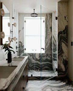 Modern minimalist bathroom featuring a marble shower and sink area with a large window.