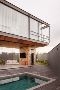 A modern residential outdoor space featuring a concrete and wood lounge area with a poolside setting.