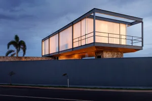 A modern residential house featuring glass walls and concrete structural elements.