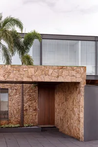 Modern residential home with stone exterior and large glass windows.