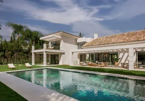 Modern villa with white rendered concrete exterior, featuring a rectangular pool and covered patio area.