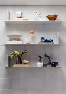 A well-organized shelf featuring ceramic, glass, and metal decorative items.