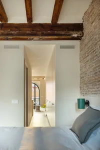 A modern bedroom featuring brick and concrete walls, with a cozy ambiance created by the natural light.