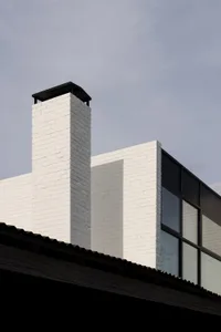A modern building with a white brick exterior and a chimney.