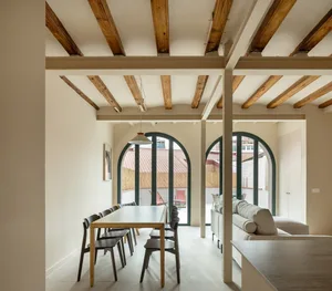 A modern interior space featuring white walls, wooden beams, and a comfortable seating area.