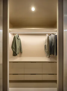 Modern closet with neutral color palette, featuring floating shelves and clothing storage.