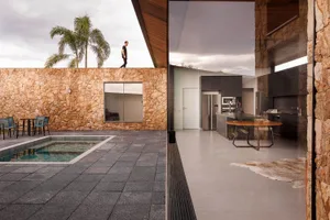 A modern residential interior featuring a concrete patio with a pool and seating area, a well-lit living space with a large k