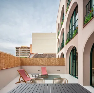 Concrete and wooden residential courtyard with pink lounge chairs and green grass.