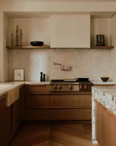 A modern residential kitchen featuring wooden cabinets, a marble countertop, and metal appliances.