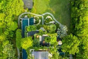 Aerial view of a modern garden landscape featuring a pool, pathways, and tropical vegetation.