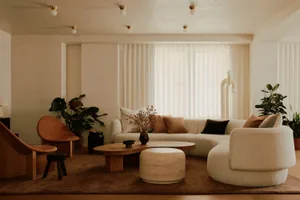 Modern minimalist living room with mid-century wood and fabric elements, featuring a large sofa, coffee table, and decorative