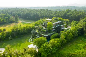 Modern residential house surrounded by green trees with green roof materials visible.