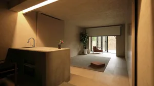 A minimalist residential kitchen with concrete cabinets, wooden flooring, and glass windows.