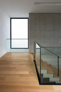 Modern architectural interior with wooden flooring, concrete walls, and glass railings