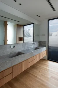 Modern bathroom with a floating concrete counter and wooden cabinets.