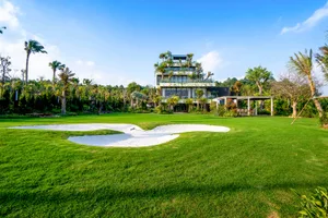 A modern landscaped garden with white sand patches surrounded by lush green grass and palm trees.