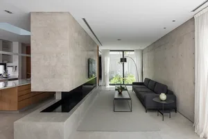 Interior design featuring modern minimalist living room with concrete walls and floor, white curtains, and gray sofa.