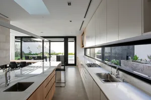 Contemporary kitchen featuring marble countertops, wooden cabinets, and large windows.