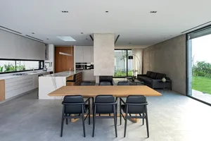 Modern minimalist living dining kitchen space with concrete, marble, and metal materials
