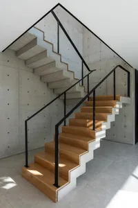 A modern staircase with wooden steps and concrete railings.