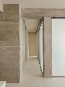 A minimalist corridor with concrete walls, minimal decor, and a long hallway.
