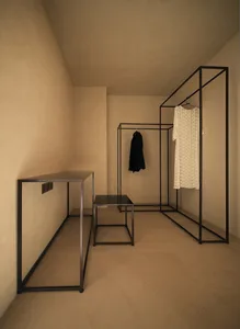 A minimalist clothing display area featuring a metal and glass structure.