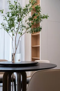 A modern interior design featuring a wooden table with a vase of greenery on top.