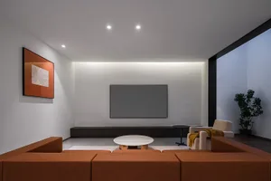 A modern living room featuring minimalist design, with large windows, contemporary furniture, and a white circular coffee tab