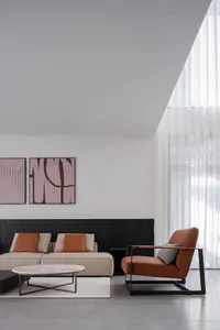 Modern minimalist living room with brown leather sofa, marble coffee table, and large screen TV.