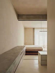A minimalist bedroom with a concrete floor cabinet and a bed with a simple frame.