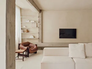 A minimalist living room with concrete shelving, a leather armchair, and a white sofa.