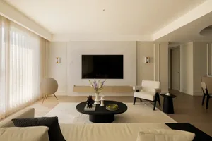 Minimalist living room interior with white walls, a black coffee table, and a large window.