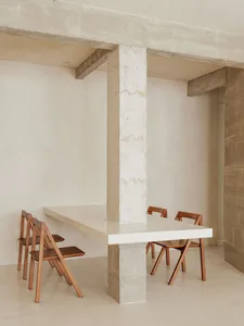 Modern minimalist dining room with concrete table and wooden folding chairs.